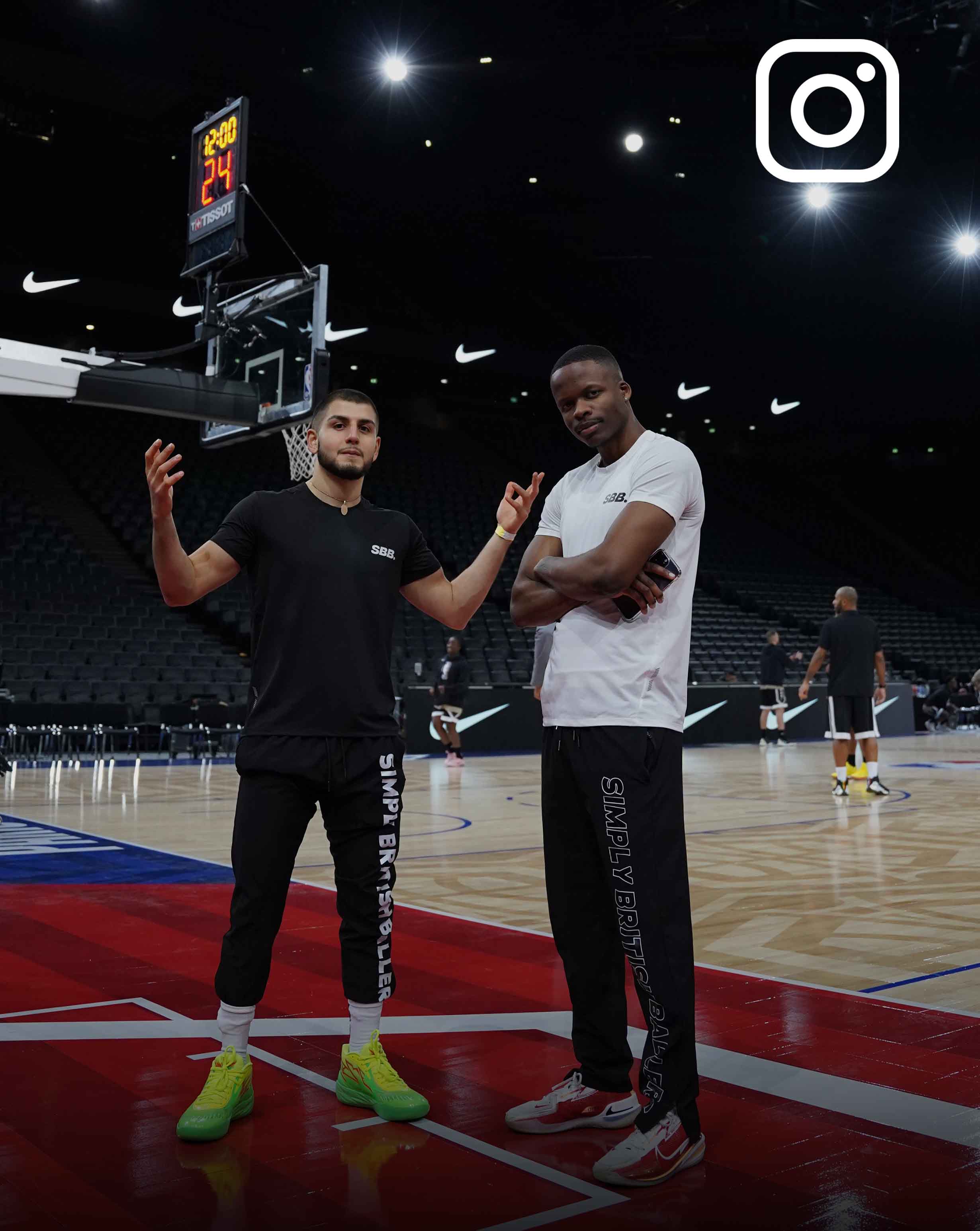 A picture of Behrad and Denzel from Simply British Ballers. (SBB.) standing on the NBA Paris Basketball Court hardwood. With an instagram logo in the top right of the image to inform the viewer this picture is linked with our instagram @sbb_uk